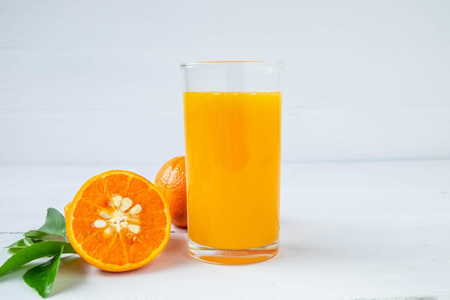 jugo de naranja fresco y naranja en la mesa foto