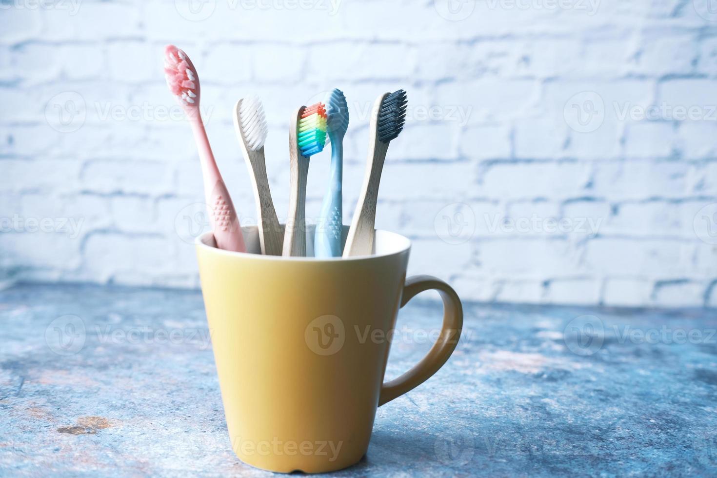 Cepillos de dientes de colores en taza blanca foto