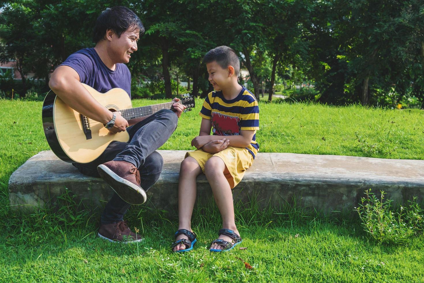 padre tocando la guitarra para su hijo foto