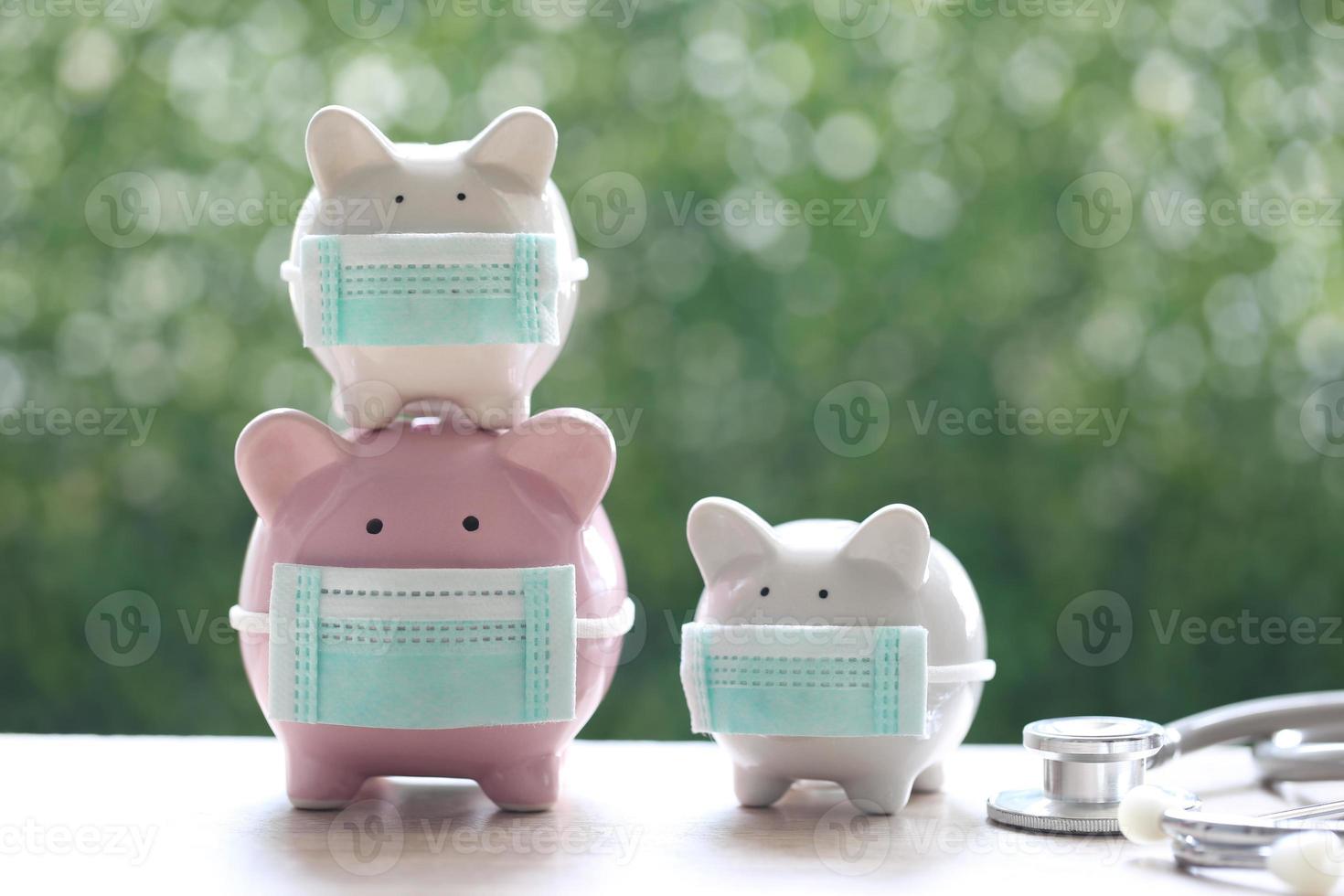 Piggy banks wearing protective medical masks on a natural green background, save money for medical insurance and health care concept photo