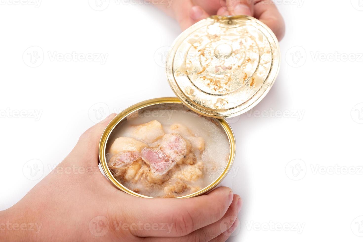 Hands opening a can of stew on a white background photo