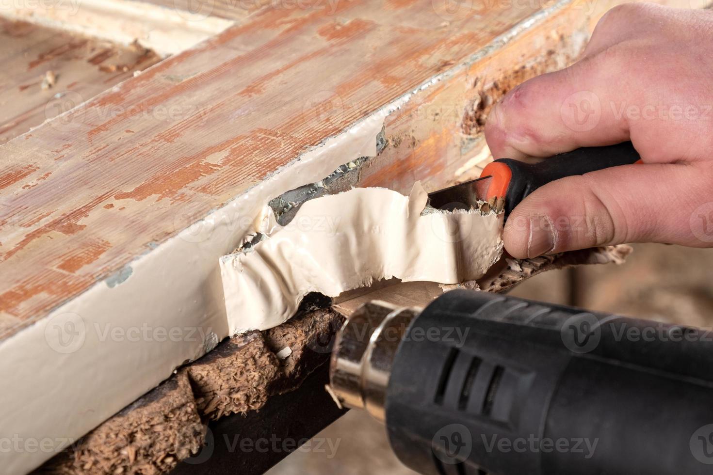 Hands cleaning old paint from a wooden door, restoration of wooden furniture photo