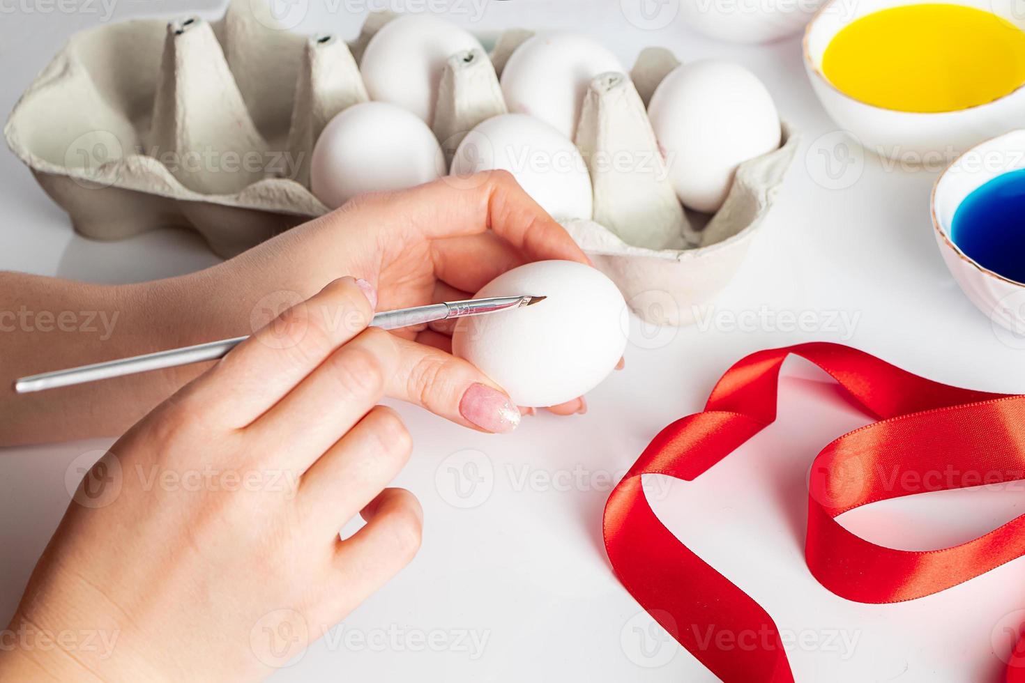 mujer joven pinta huevos blancos para pascua. foto