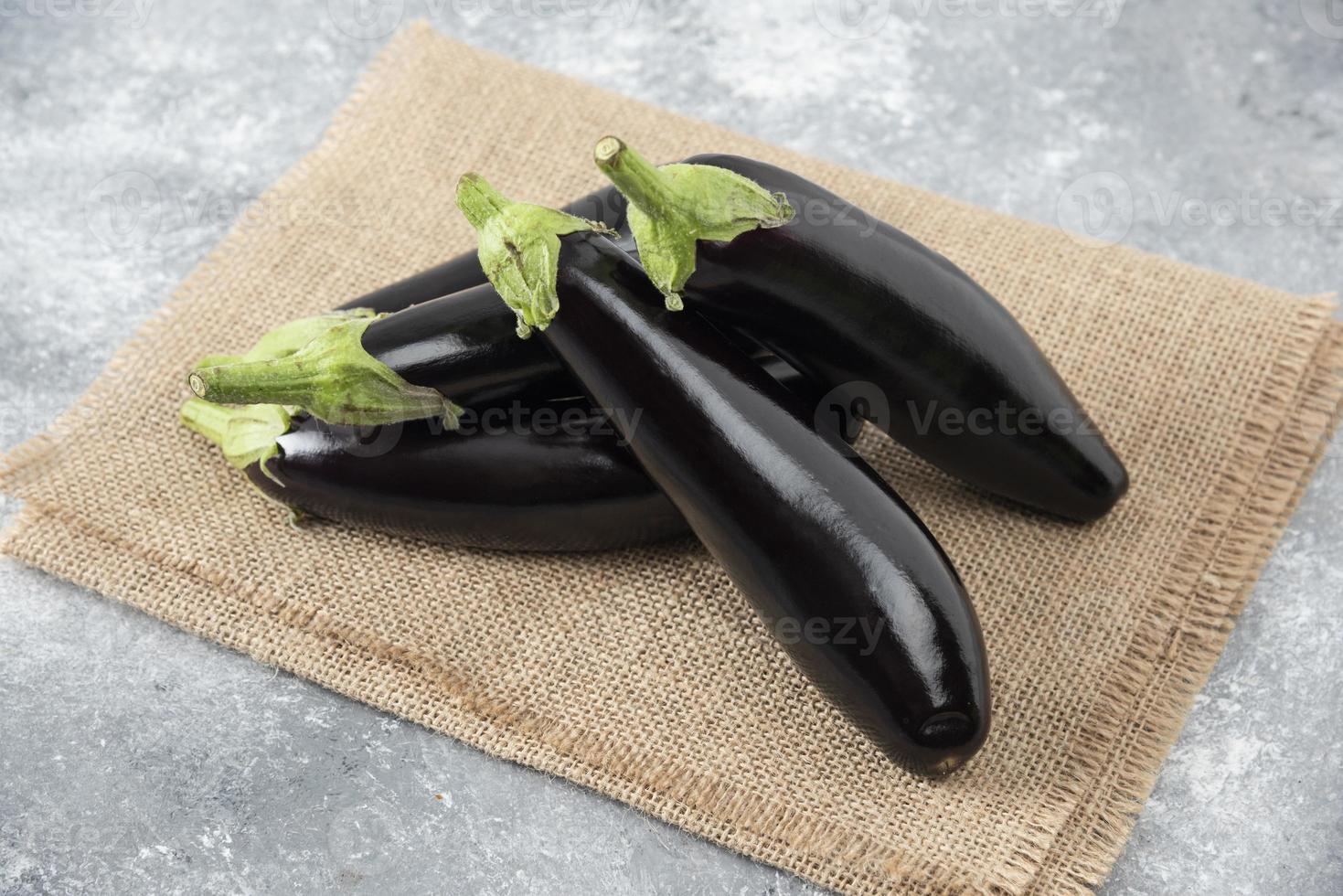 Fresh raw eggplant vegetables placed on a sackcloth surface photo