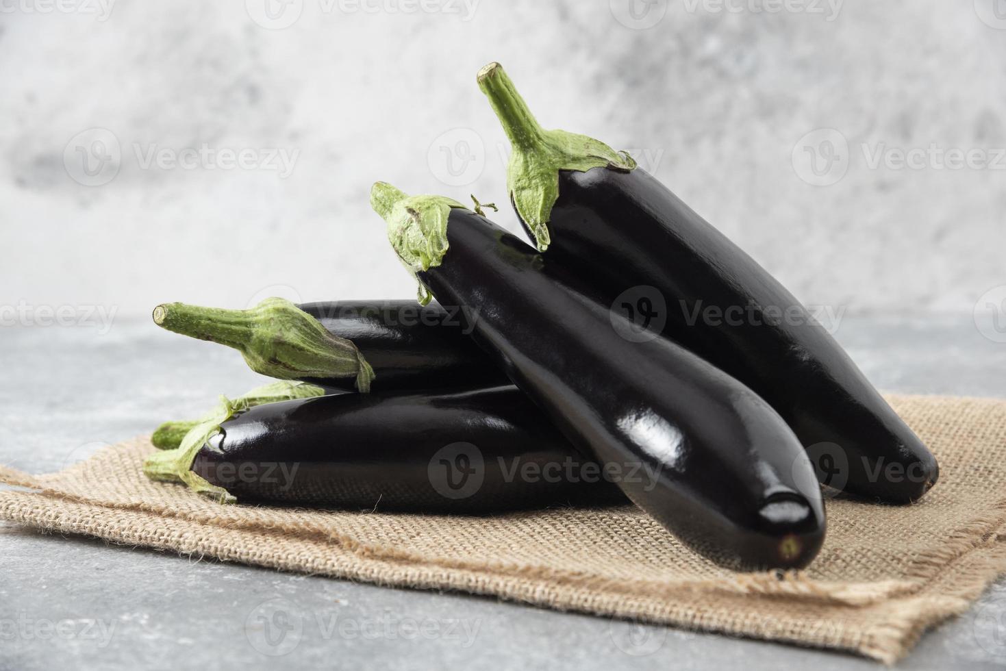 Fresh raw eggplant vegetables placed on a sackcloth surface photo