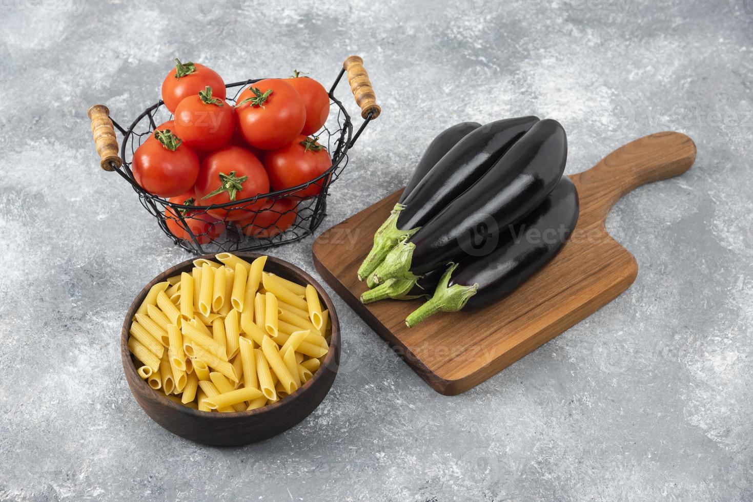 Pasta cruda con verduras frescas maduras colocadas sobre una mesa de piedra foto