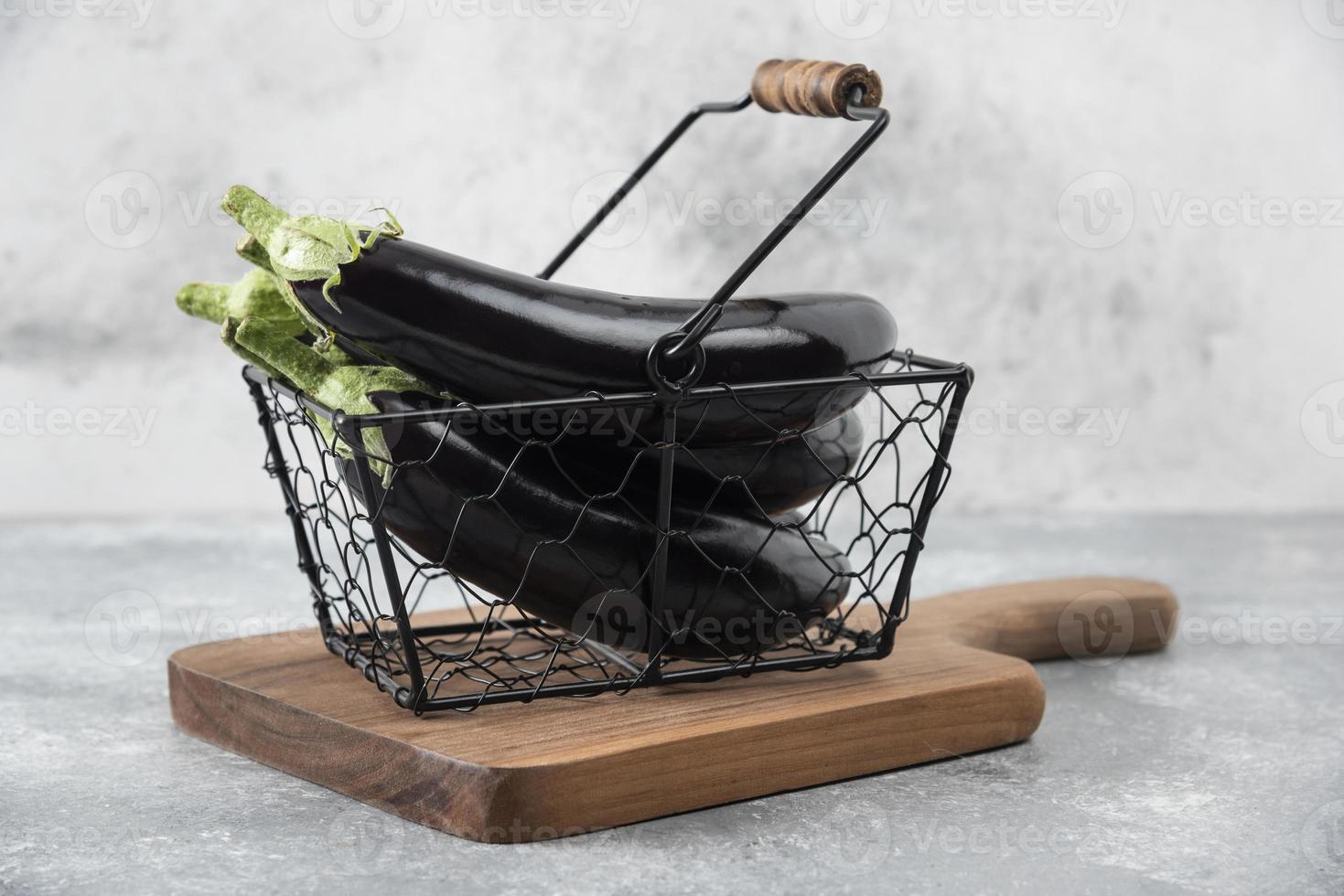 Fresh raw eggplant vegetables placed in a metallic basket photo