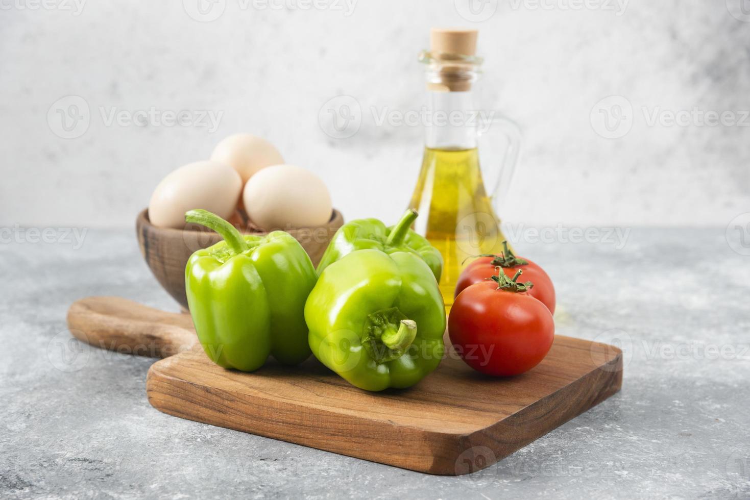 Raw chicken eggs with a glass bottle of oil and fresh vegetables photo