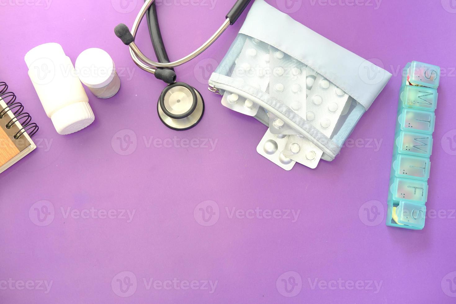 Blister pack, thermometer, and stethoscope on purple background photo