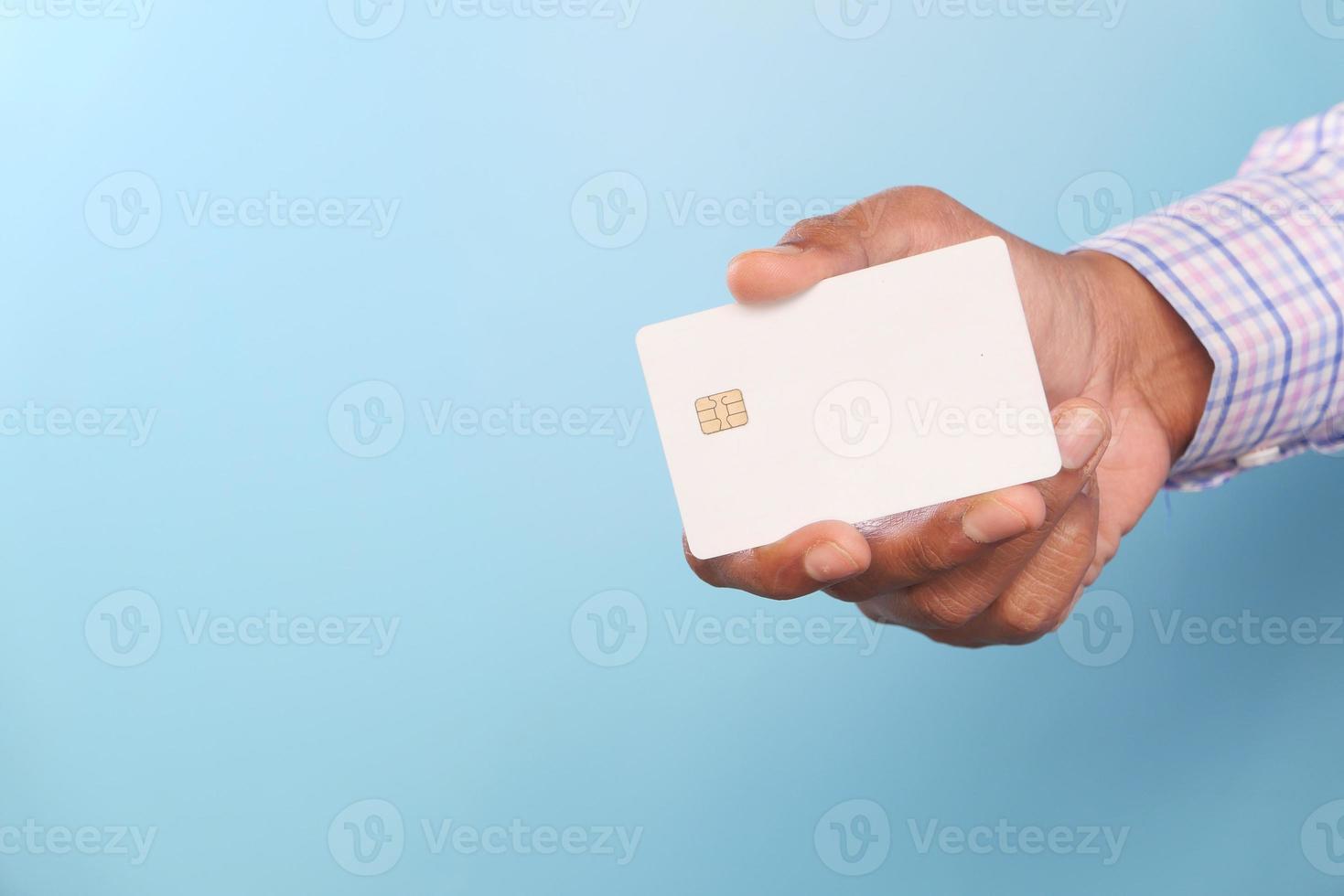 Man's hand holding credit card against blue background photo