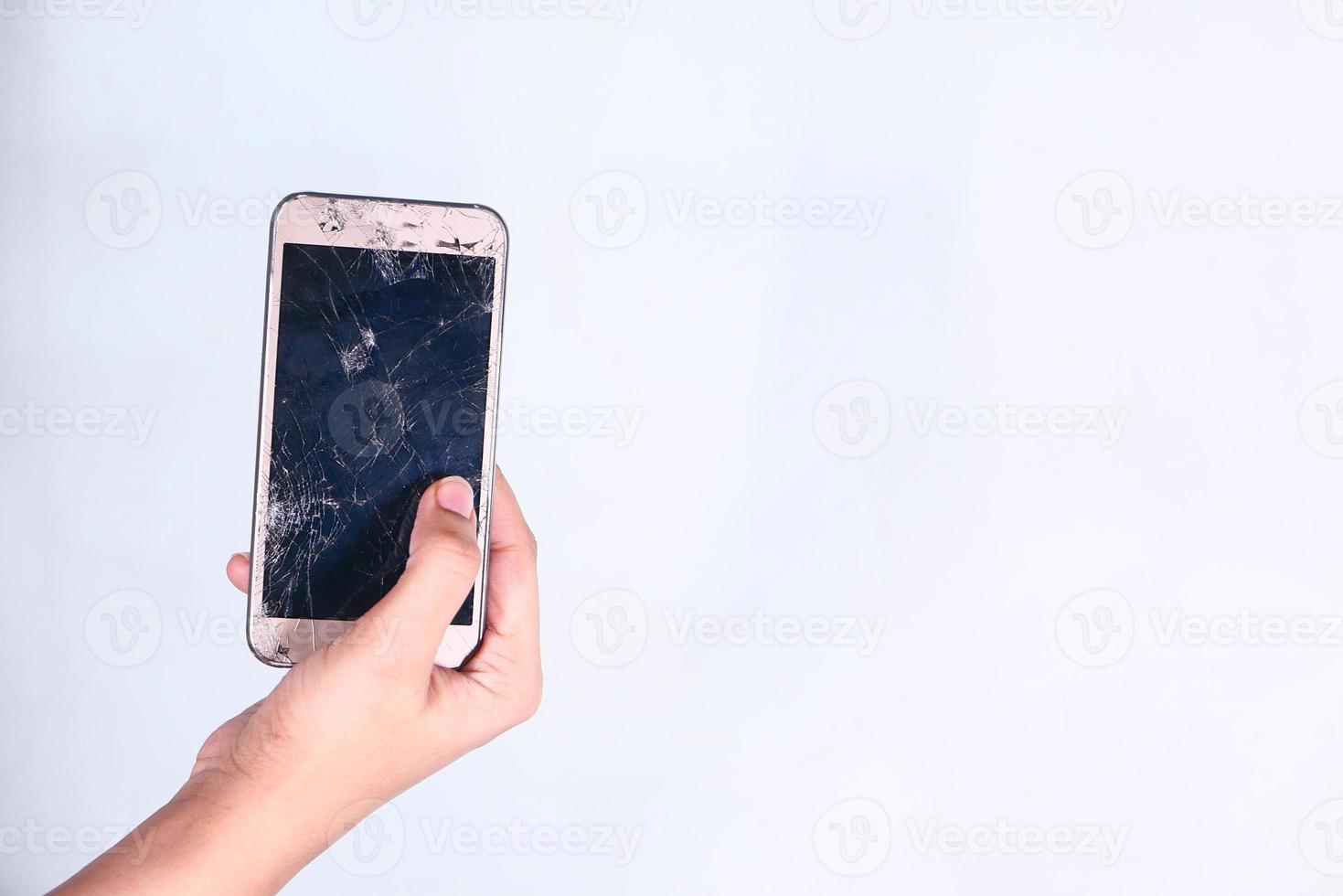 Cerca de mujer sosteniendo teléfono inteligente roto aislado en blanco foto