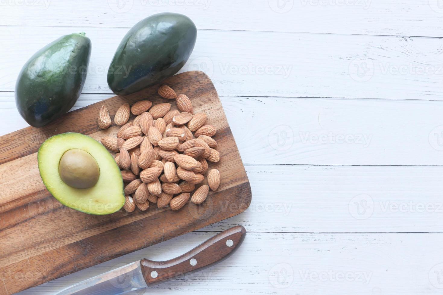 Aguacate y almendras a la mitad sobre una tabla de cortar foto