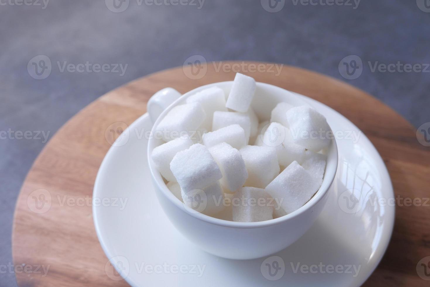 Cup of sugar cubes on table photo