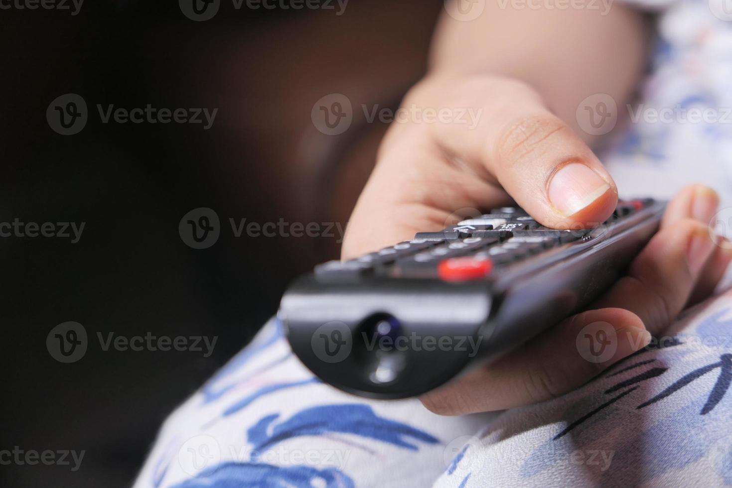 Cerca de la mano de mujer sosteniendo el control remoto foto