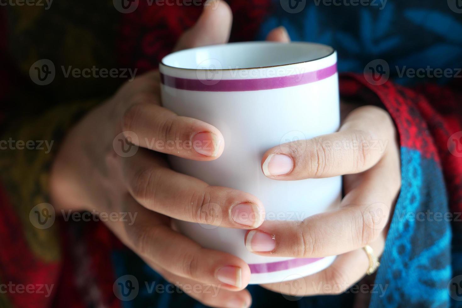Cerca de la mano de mujer sosteniendo la taza de café foto