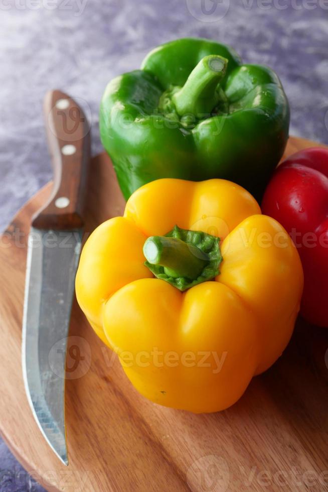 Yellow, green, and red capsicum on wooden background photo