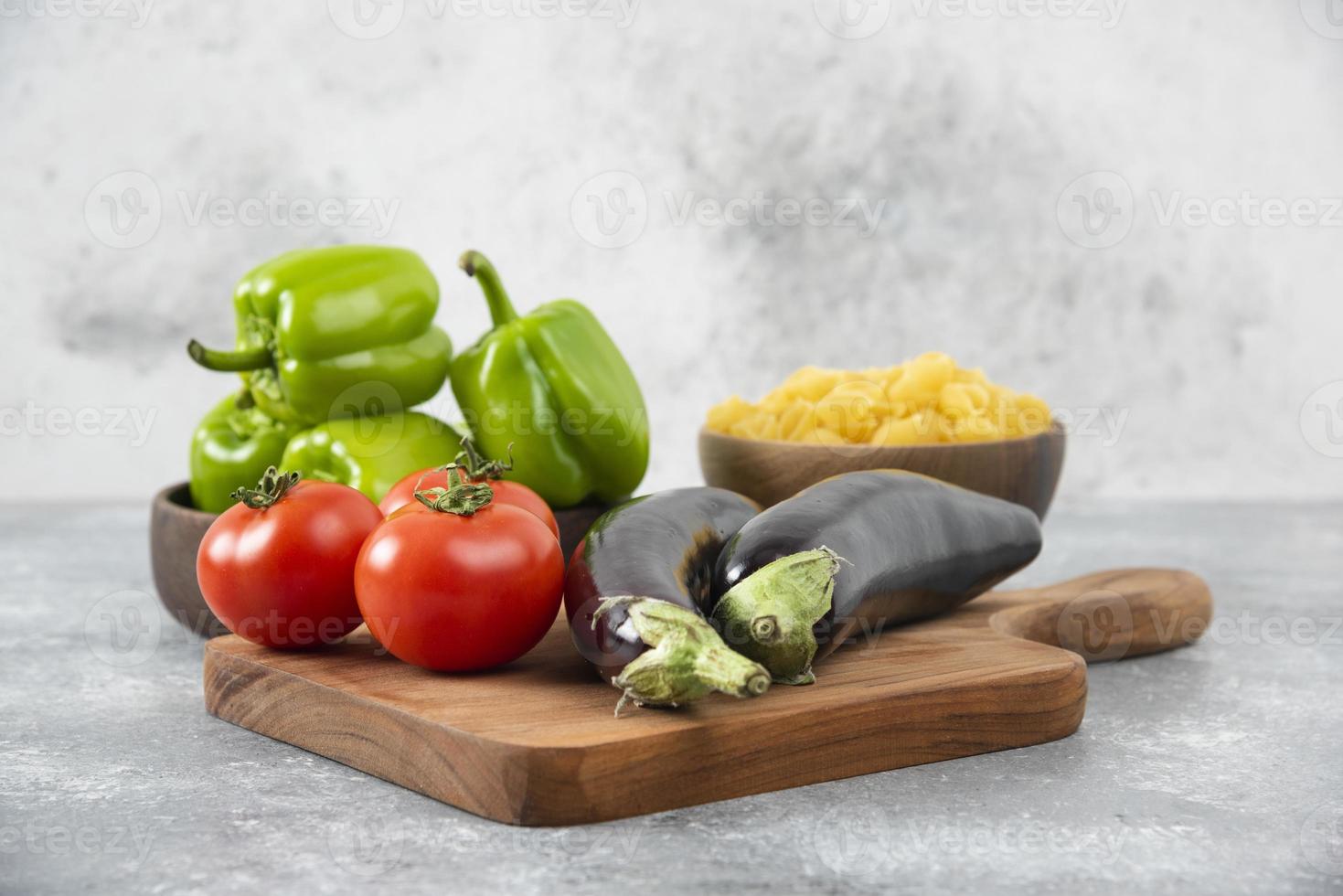 Verduras frescas maduras con un cuenco de madera lleno de pasta cruda en forma de concha foto