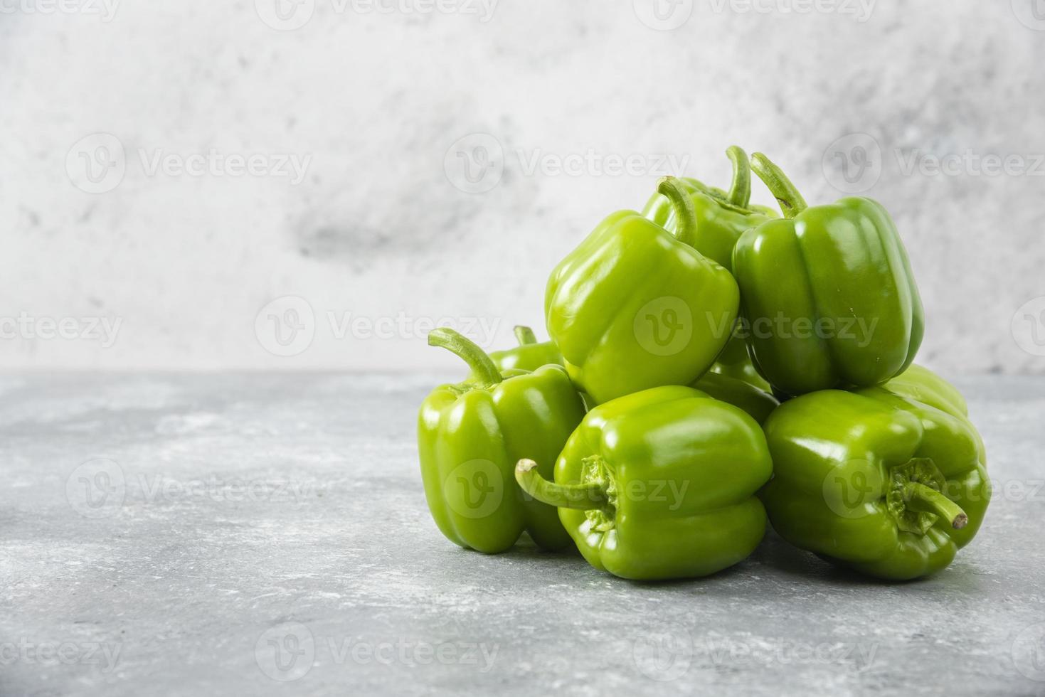 Pimientos verdes frescos colocados sobre un fondo de piedra foto