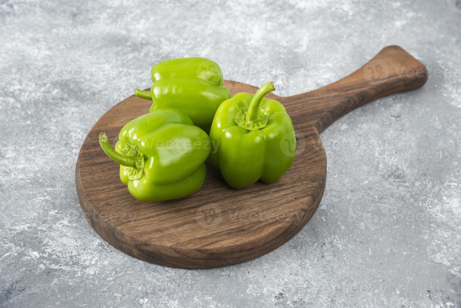 pimientos verdes frescos colocados sobre una tabla redonda de madera foto