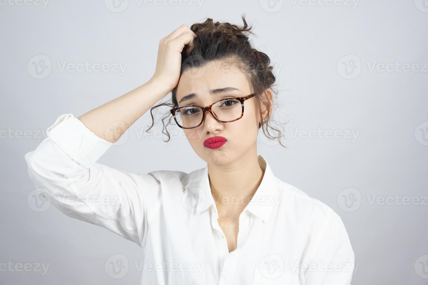 Foto de una joven mujer de pelo rizado con gafas posando para la cámara