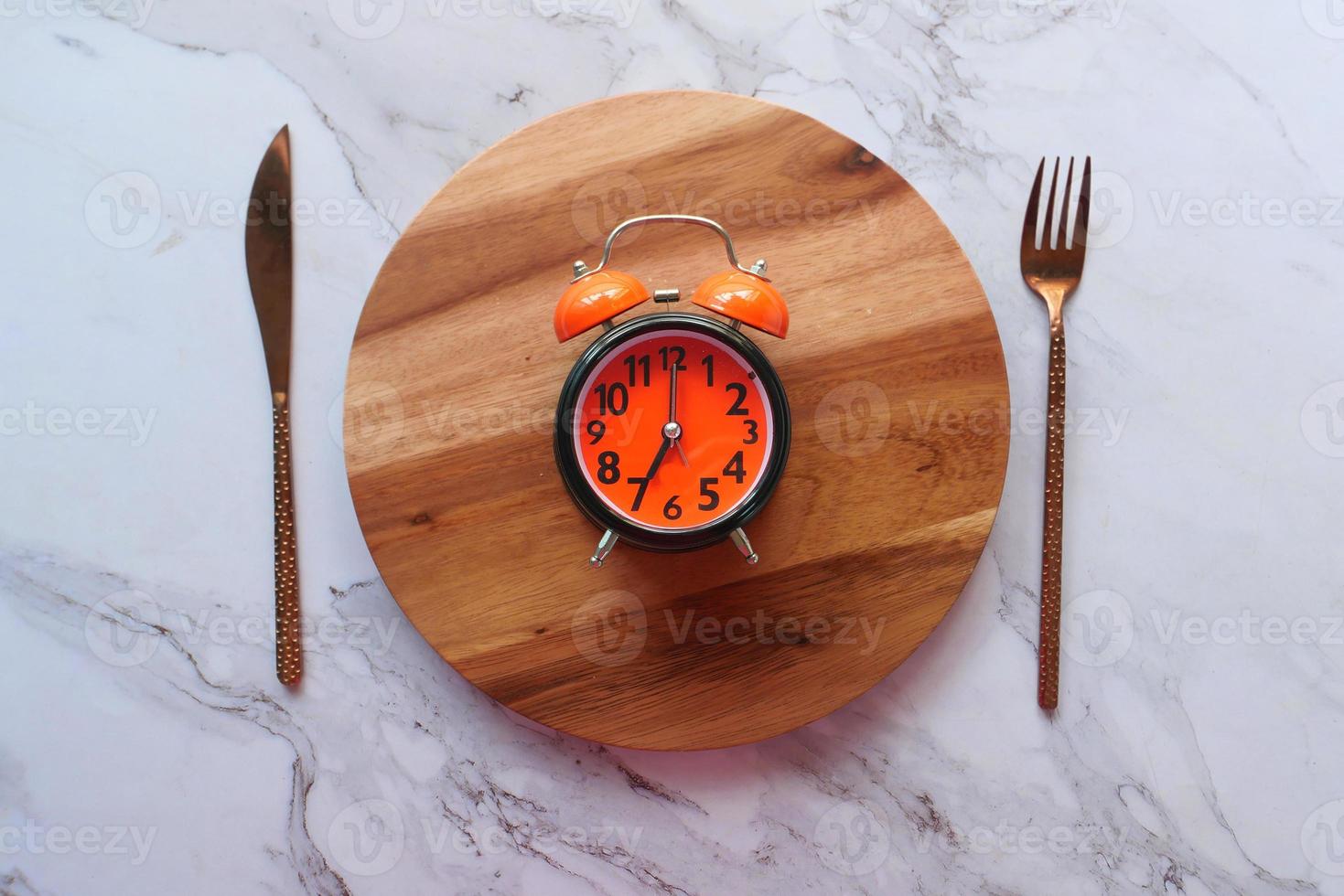 Despertador en placa de madera, concepto de la hora del desayuno foto