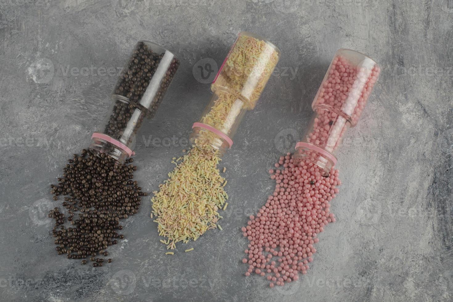 Three bottles of colorful sprinkle dotes on a marble background photo