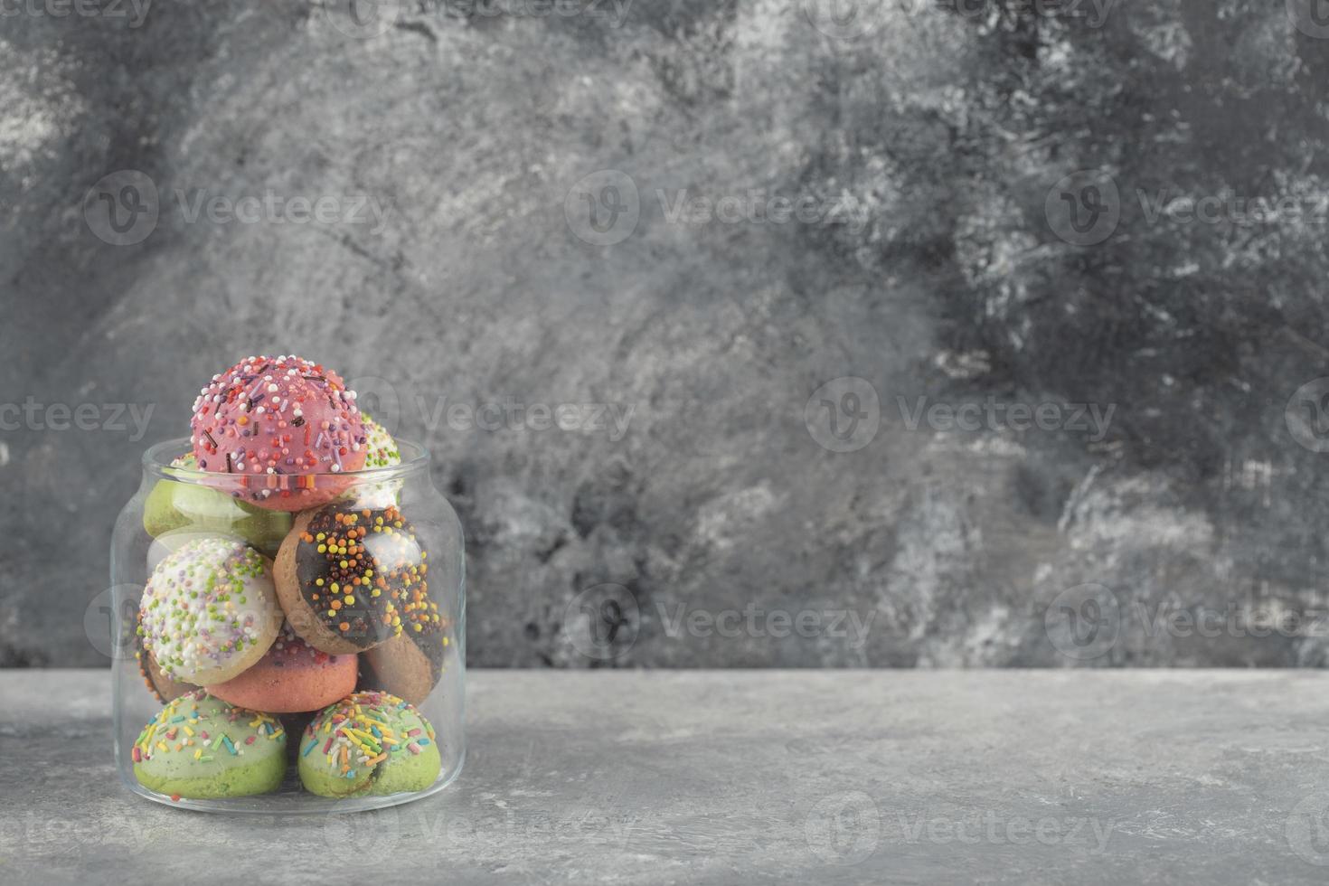 un frasco de vidrio lleno de pequeñas rosquillas de colores foto