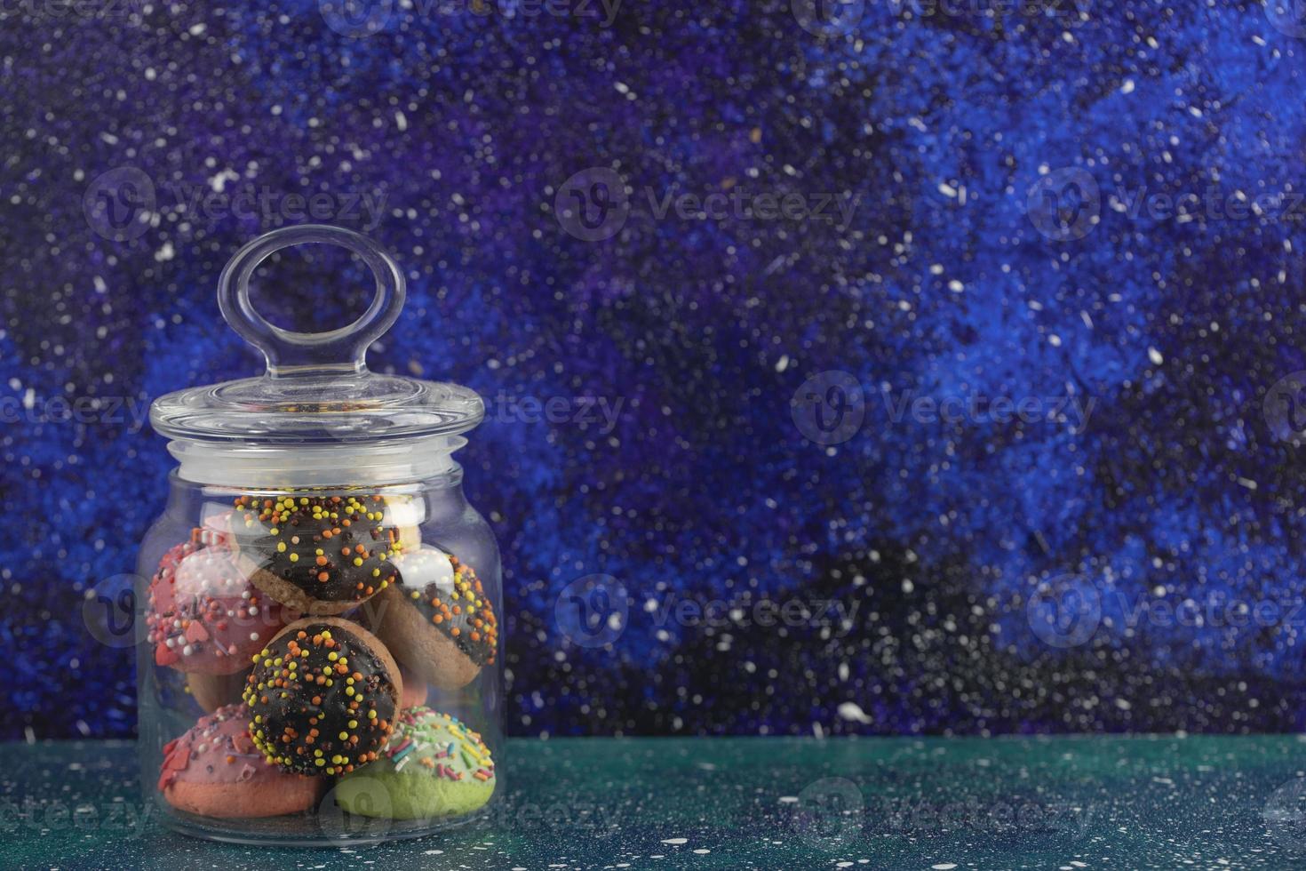 un frasco de vidrio lleno de pequeñas rosquillas de colores foto