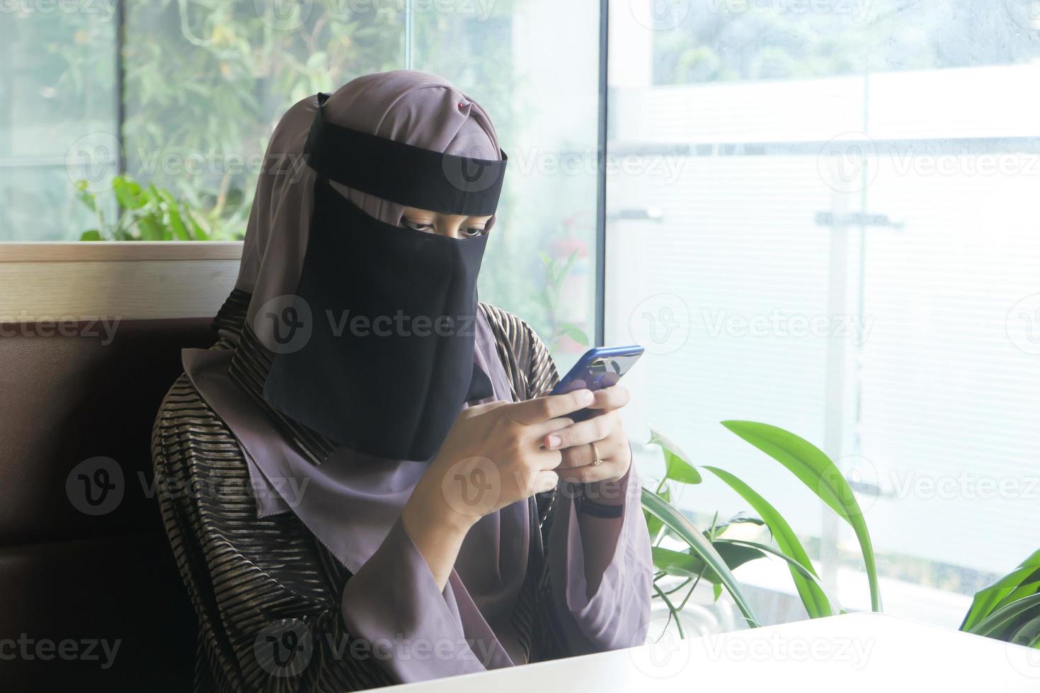 Las mujeres musulmanas con pañuelo en la cabeza con teléfonos inteligentes en el interior foto