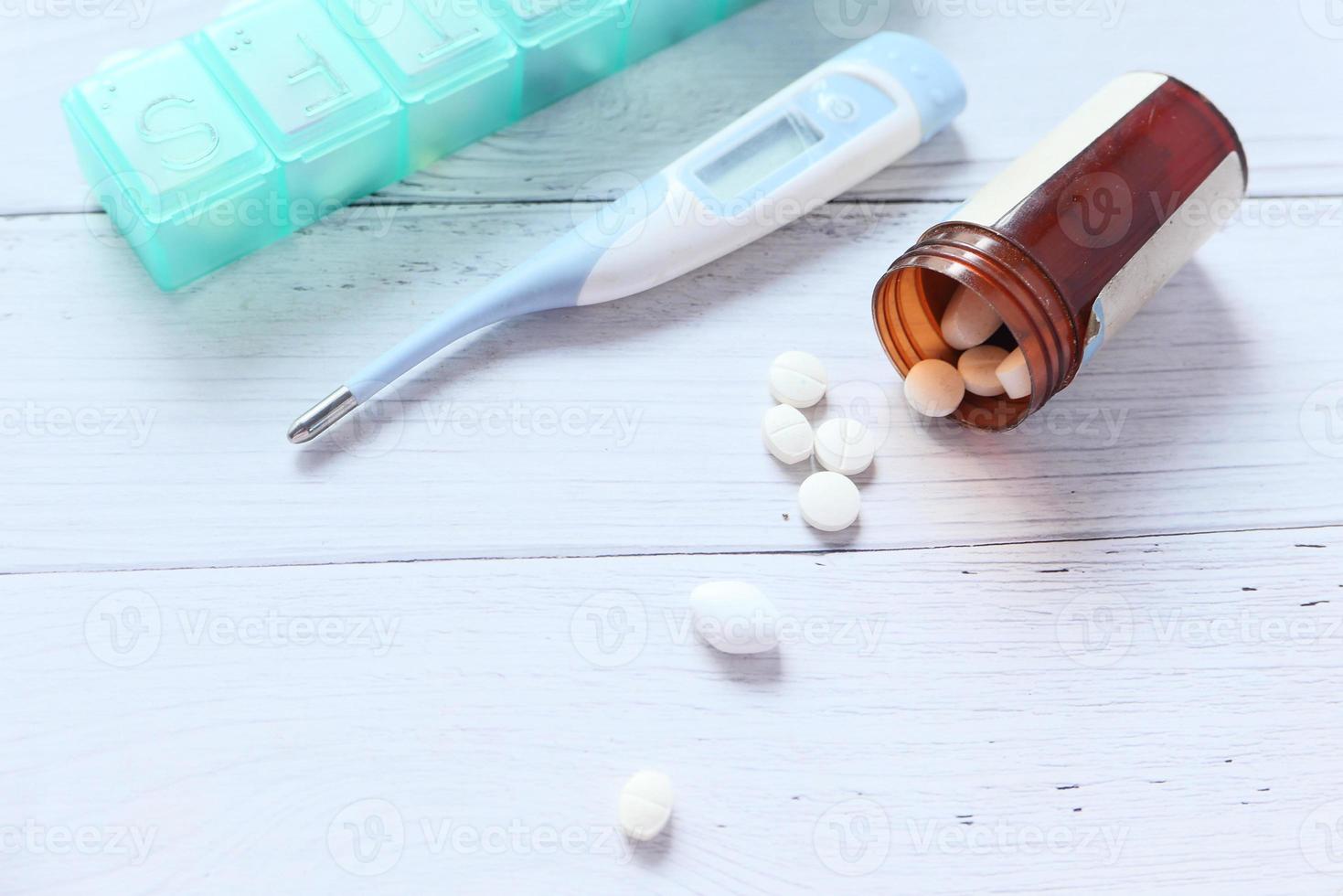 Close up of pills and thermometer on neutral background photo