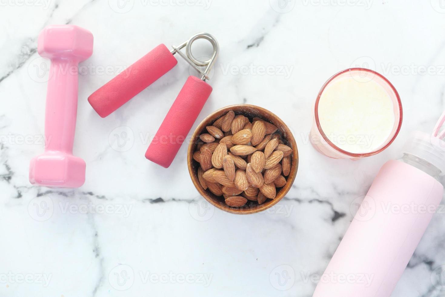 Almonds, dumb bells, and a water bottle on marble background photo