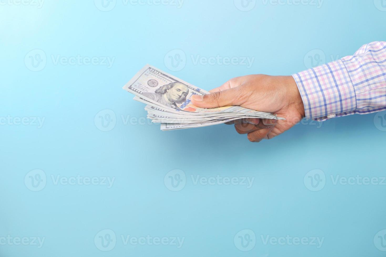 Persona que tiene muchos dólares estadounidenses sobre fondo azul. foto