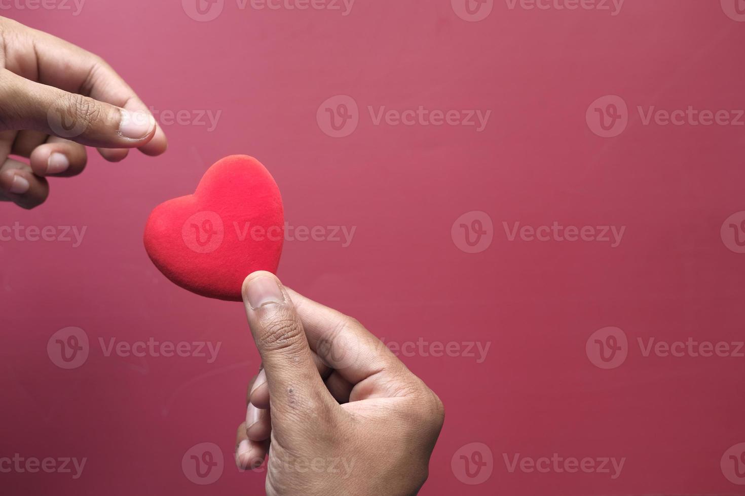 Man's hand with heart on red background photo