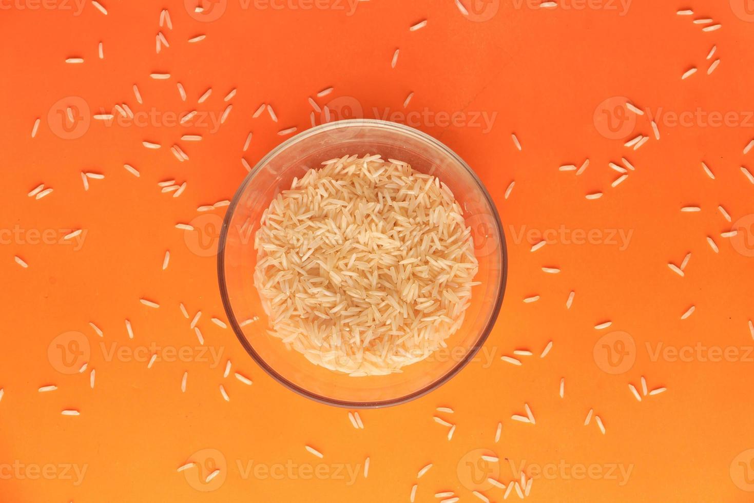Cerca de arroz integral de grano largo sobre fondo naranja foto