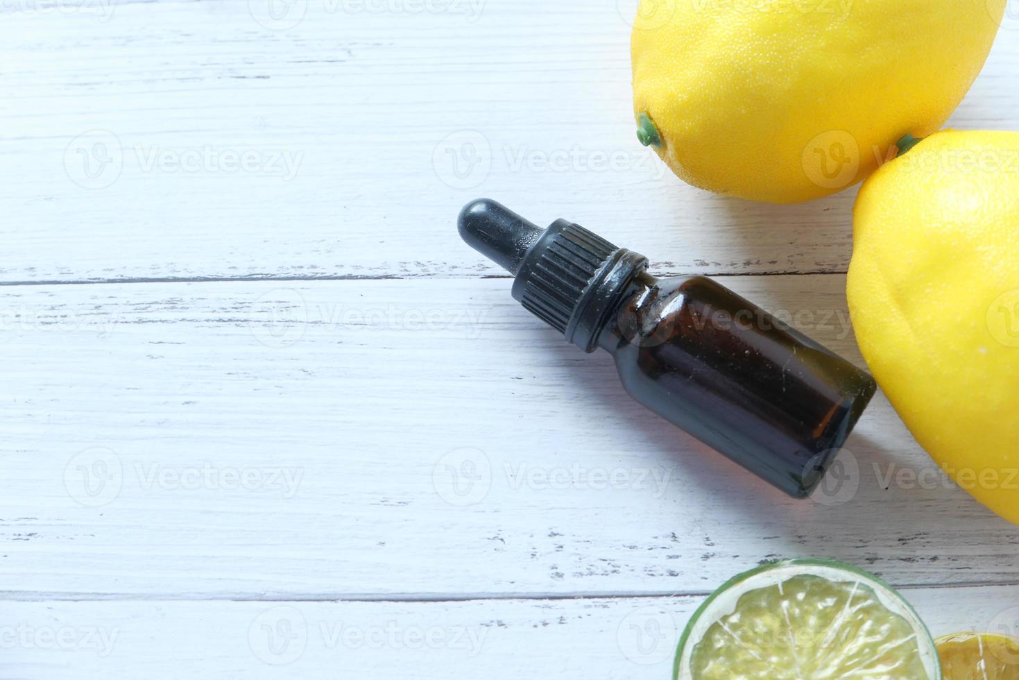 Essential oil bottle with lemon on table photo