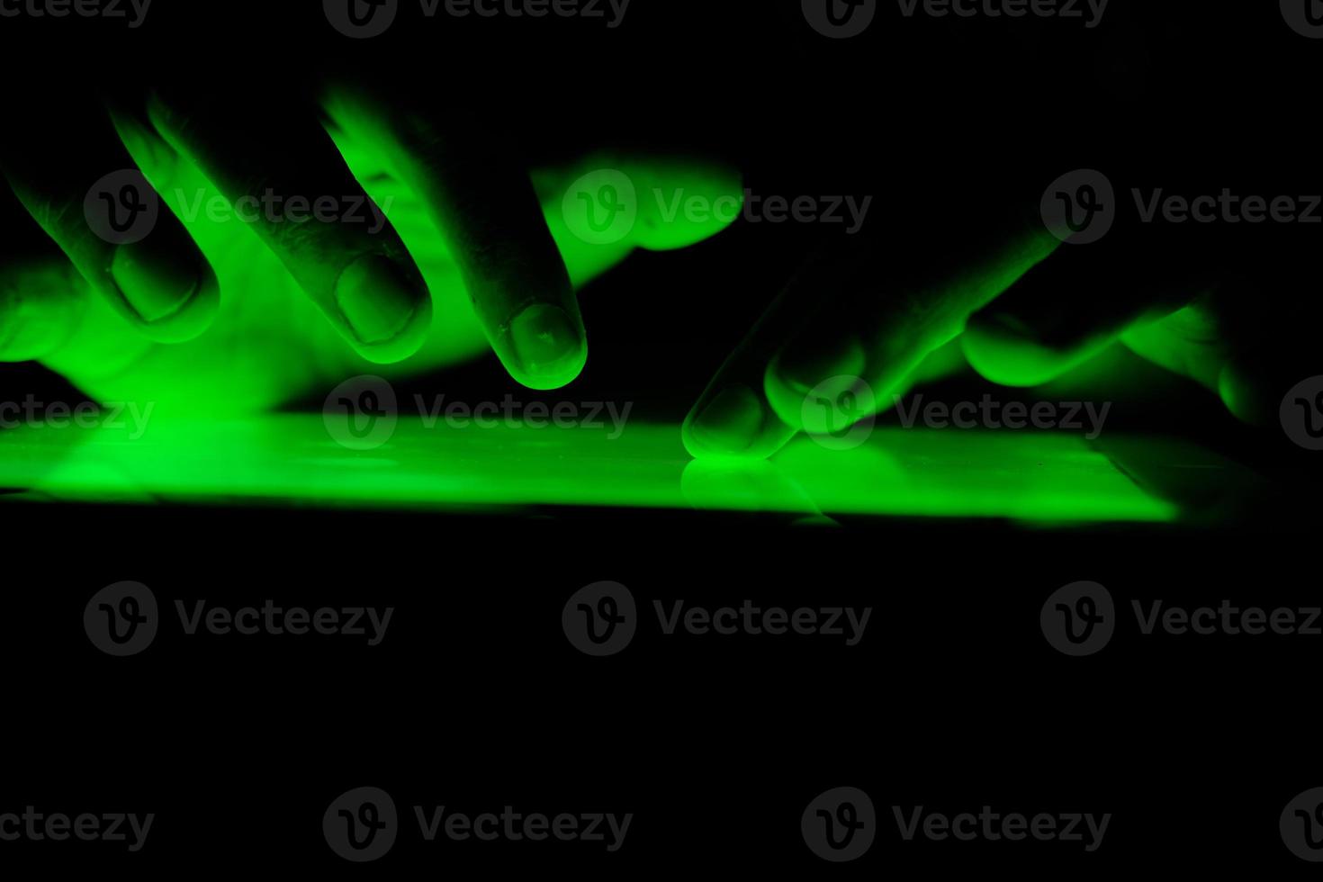 Close up of hands using a tablet with green light photo