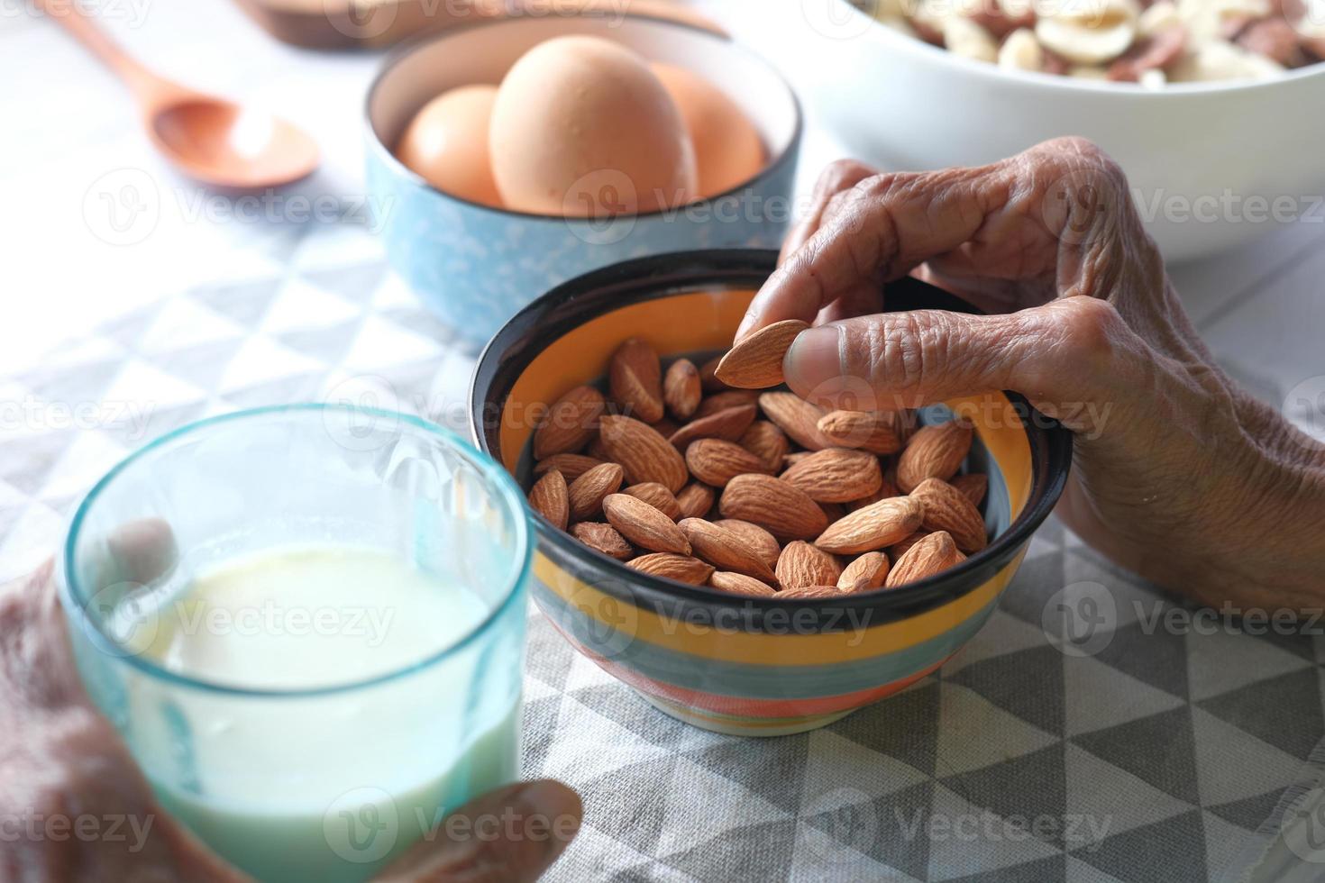 Senior woman eating almonds from a bowl photo