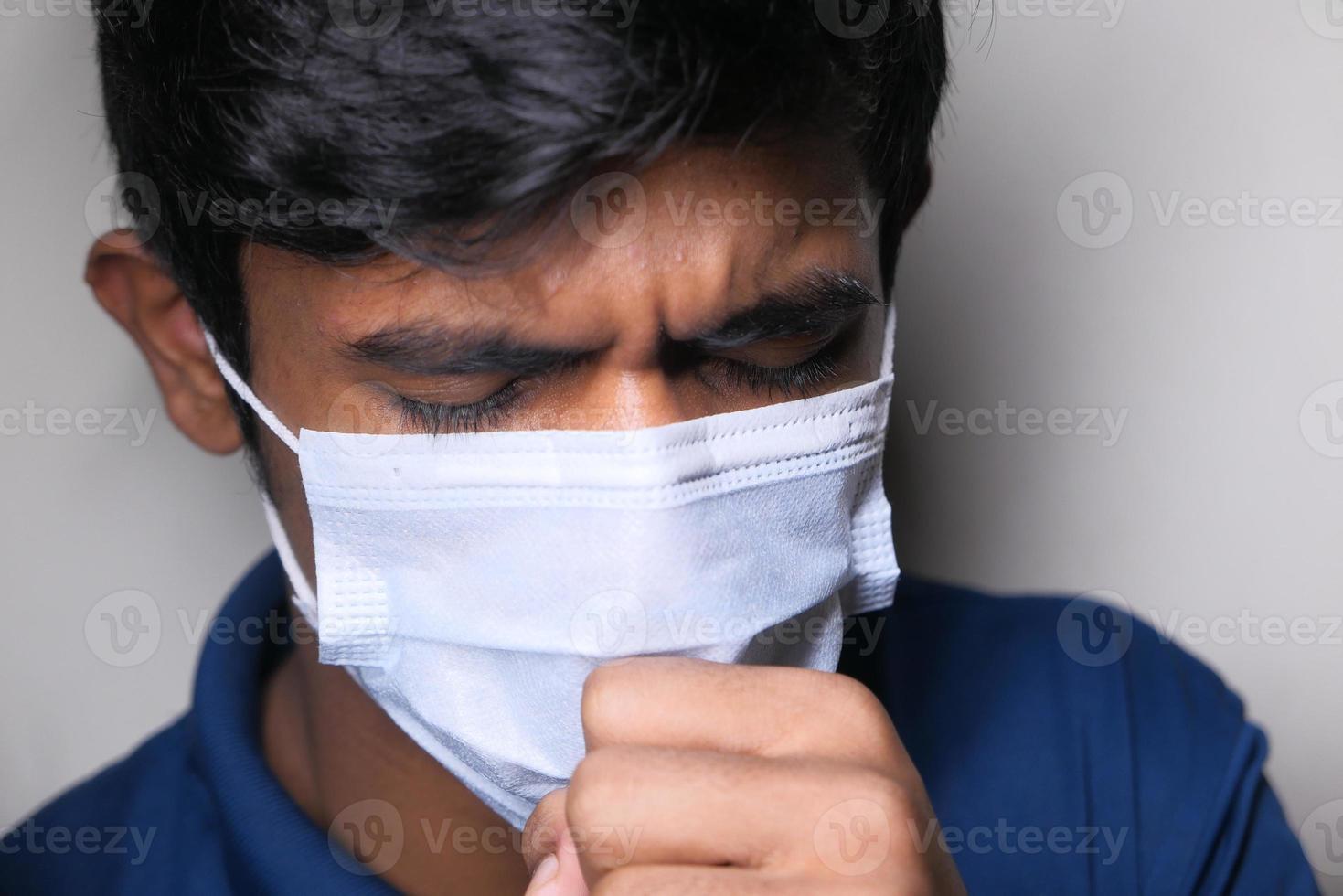 Young man coughing while wearing mask photo