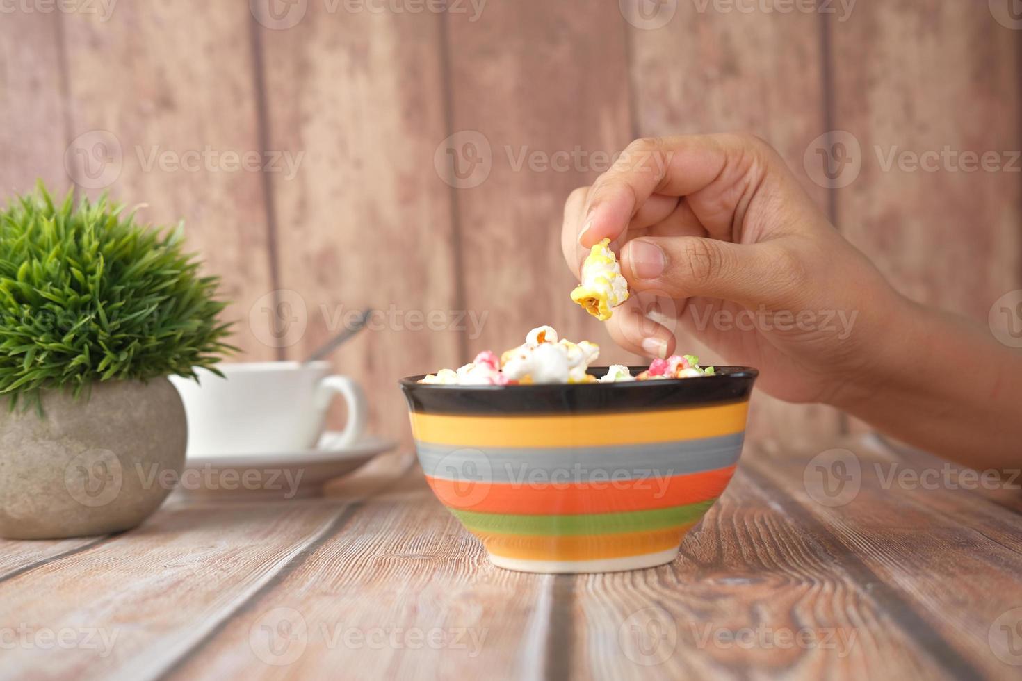 Person eating colorful bowl of popcorn photo