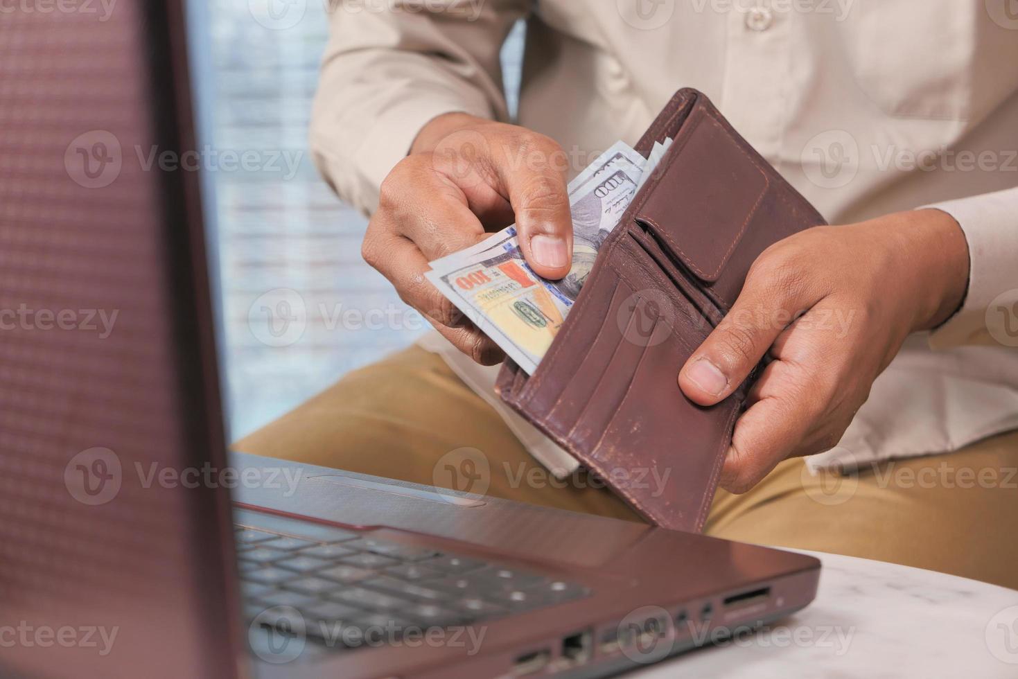 Man taking money out of brown wallet photo