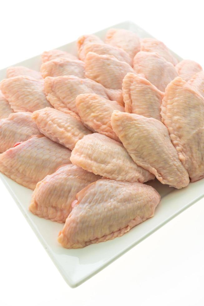 La carne de pollo cruda y el ala en la placa blanca. foto