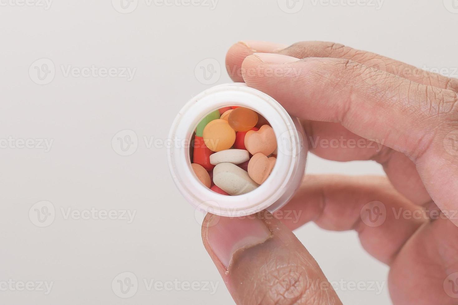 Person holding white pill bottle photo