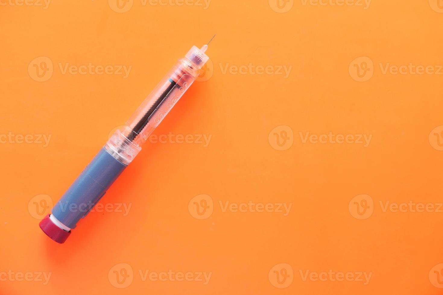 pluma de insulina sobre fondo naranja foto