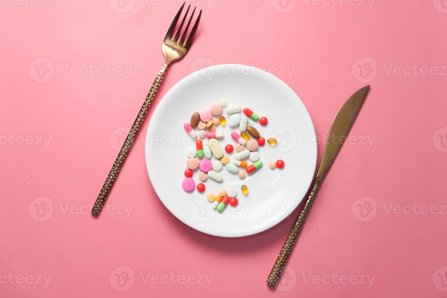 Pastillas de colores en un plato con fondo de color rosa foto