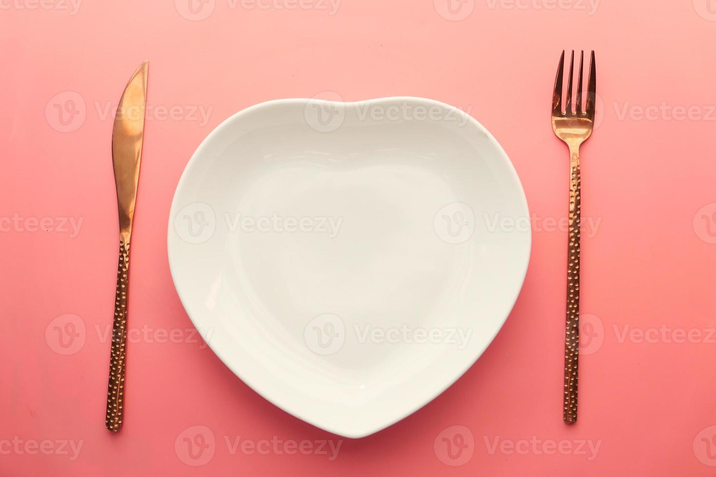 plato en forma de corazón con cubiertos de oro foto