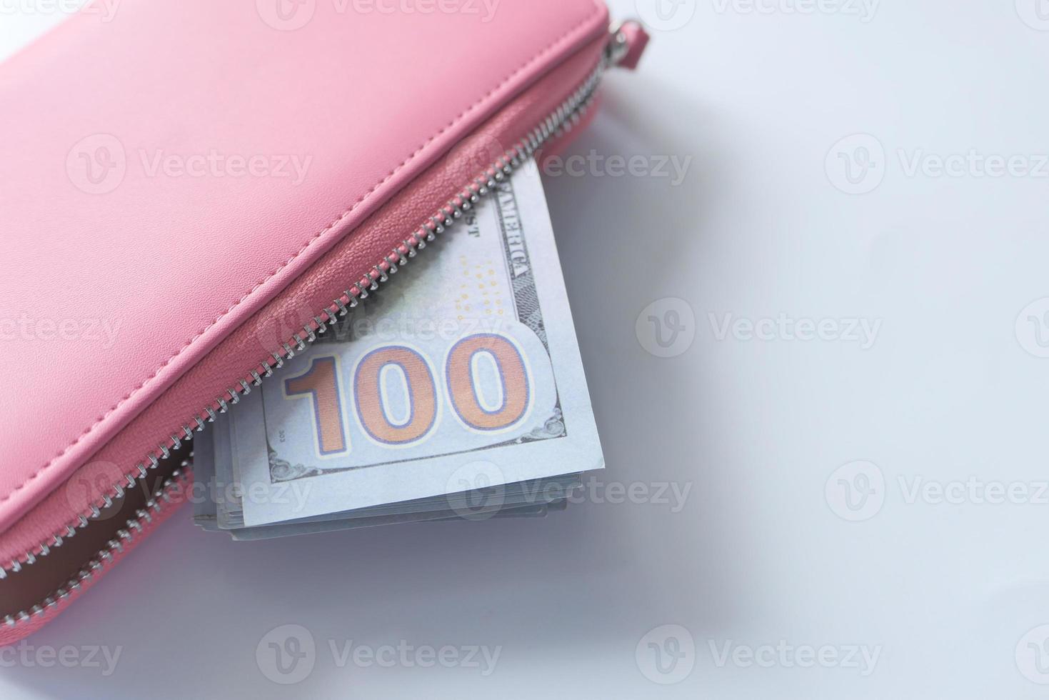 Billete de 100 dólares en cartera de piel rosa foto