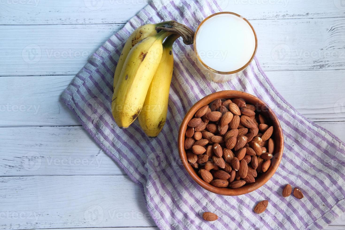 almendras, plátanos y un vaso de leche en la mesa foto