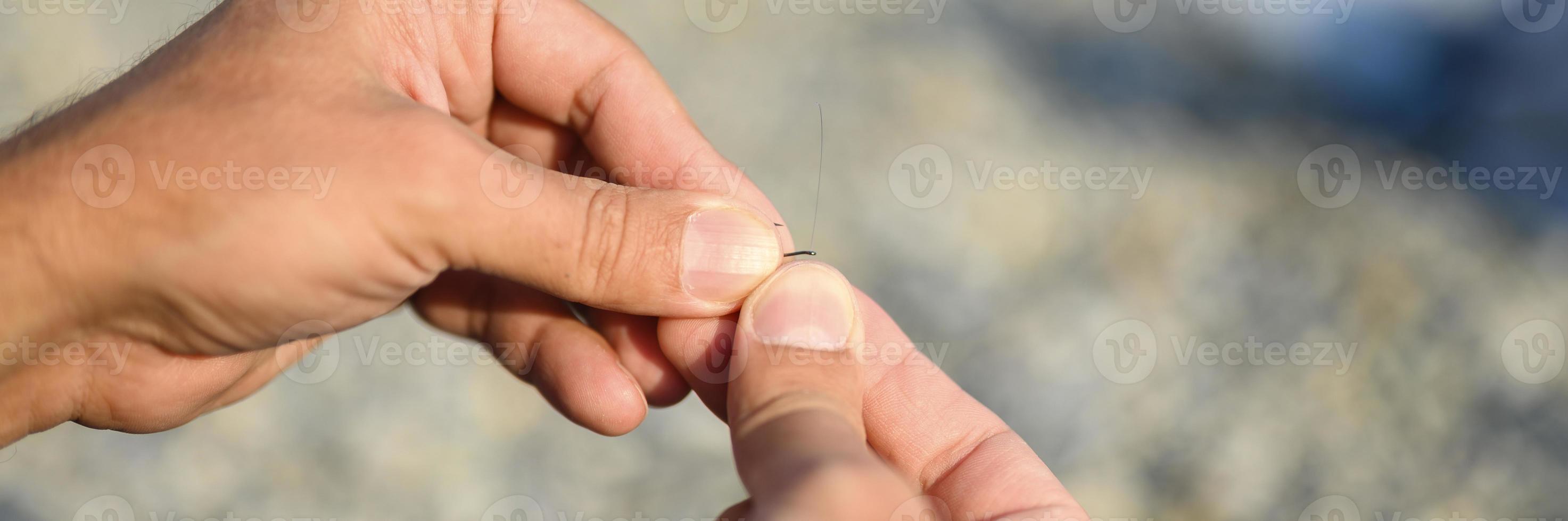 Las manos del hombre atando un hilo de pescar en un anzuelo de pesca foto