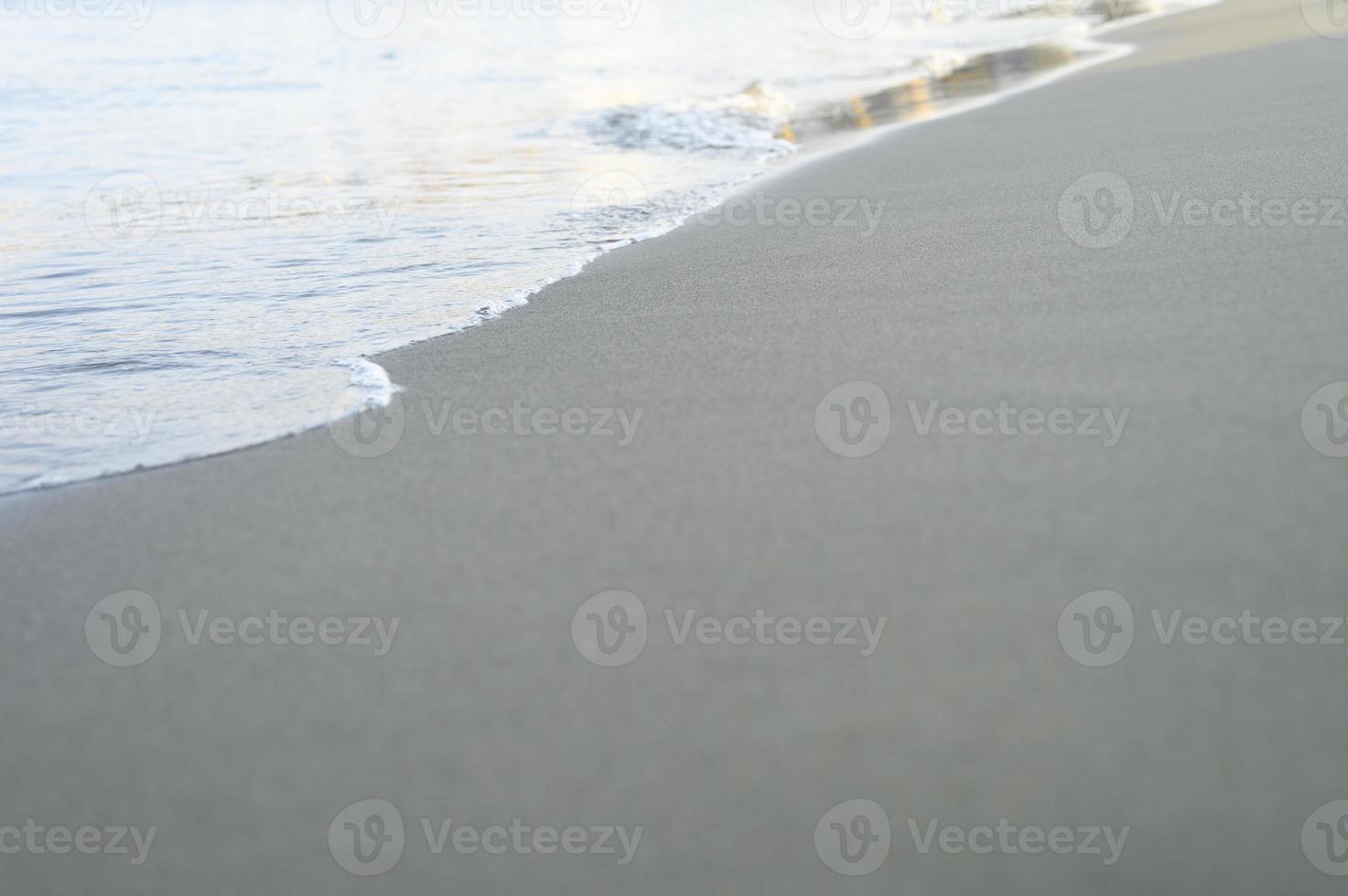 Ola borrosa del mar en la playa de arena de la tarde foto