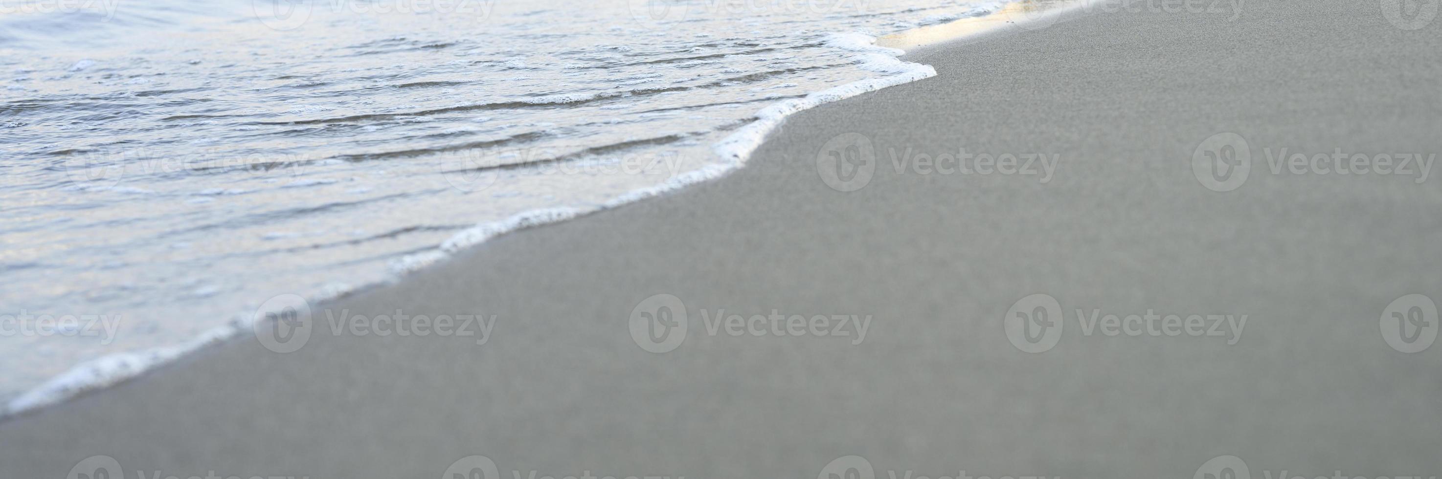 Blurred wave of the sea on the evening sand beach photo